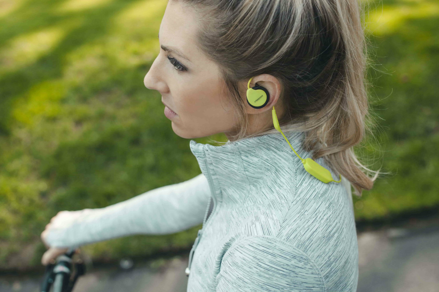 Woman riding bicycle while listening to Versafit Wireless Sport Headphones